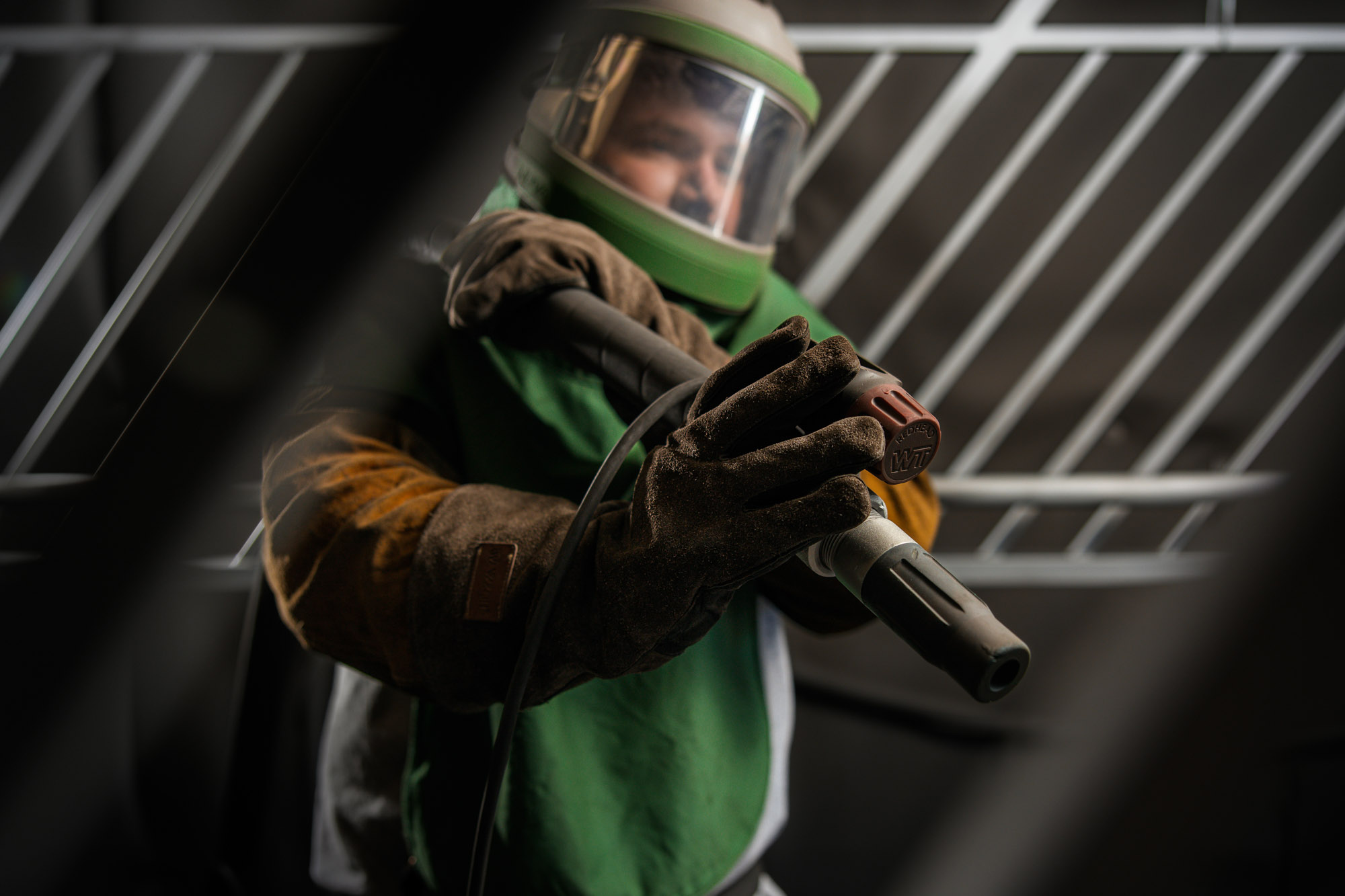 Worker using protective gear for metalwork task.
