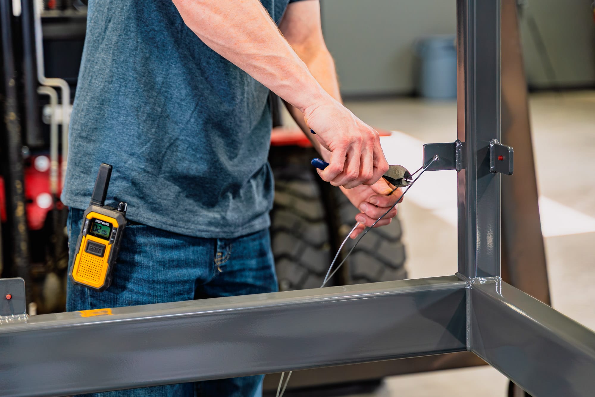 Worker cutting wire on metal frame with pliers