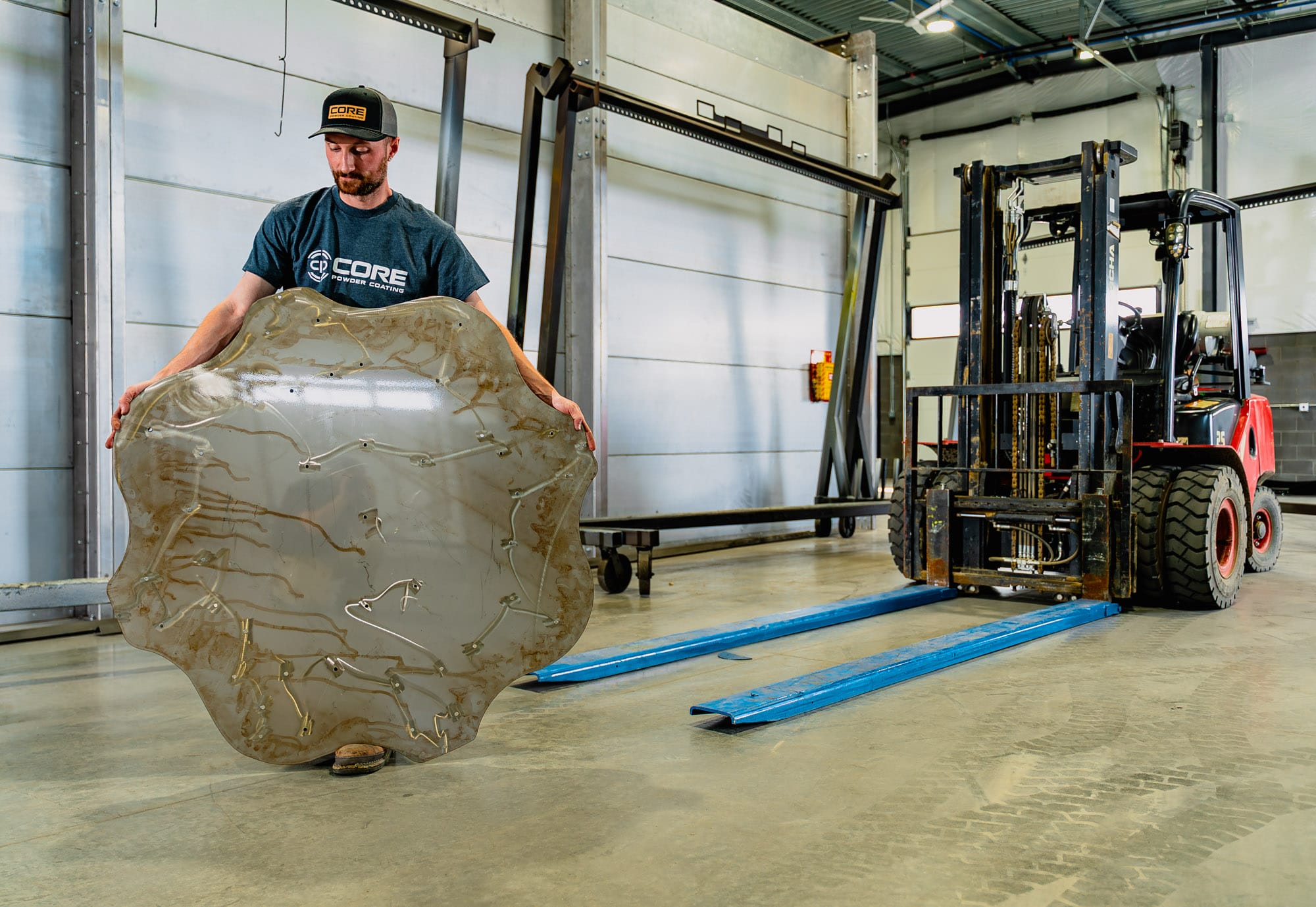 Man holding large metal panel in workshop
