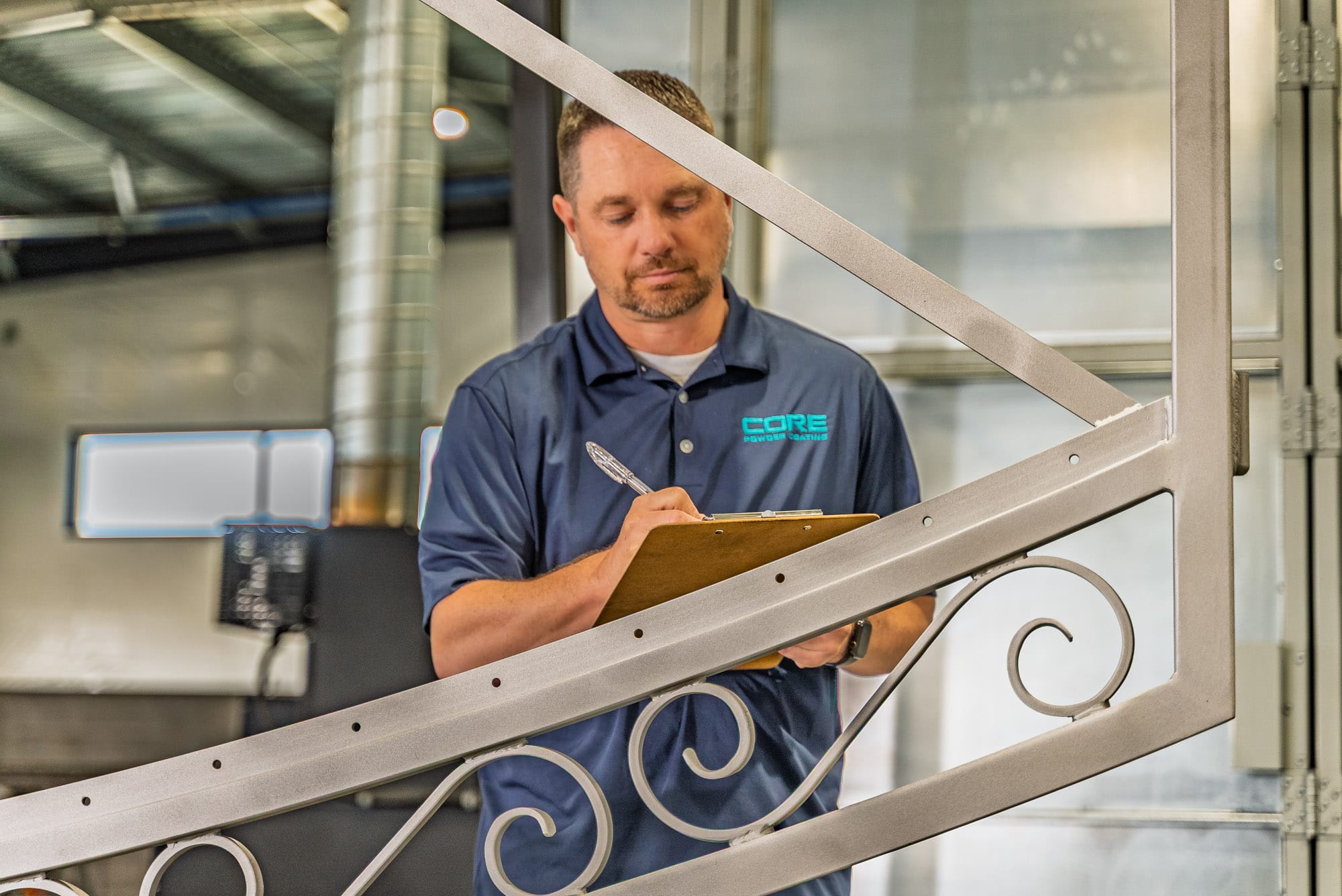 Technician inspecting metal railing with clipboard in workshop