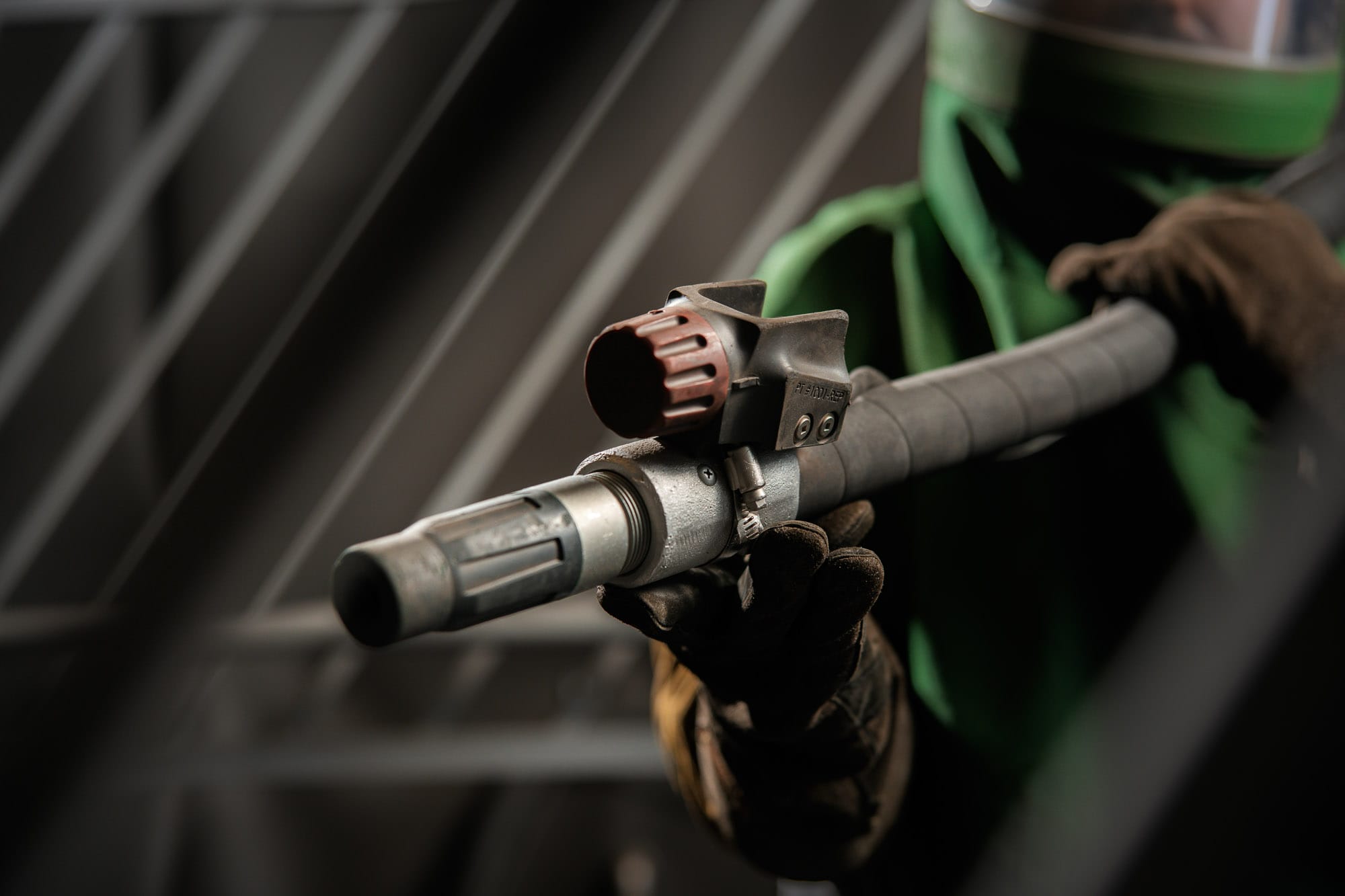 Worker holding industrial blasting nozzle in protective gear