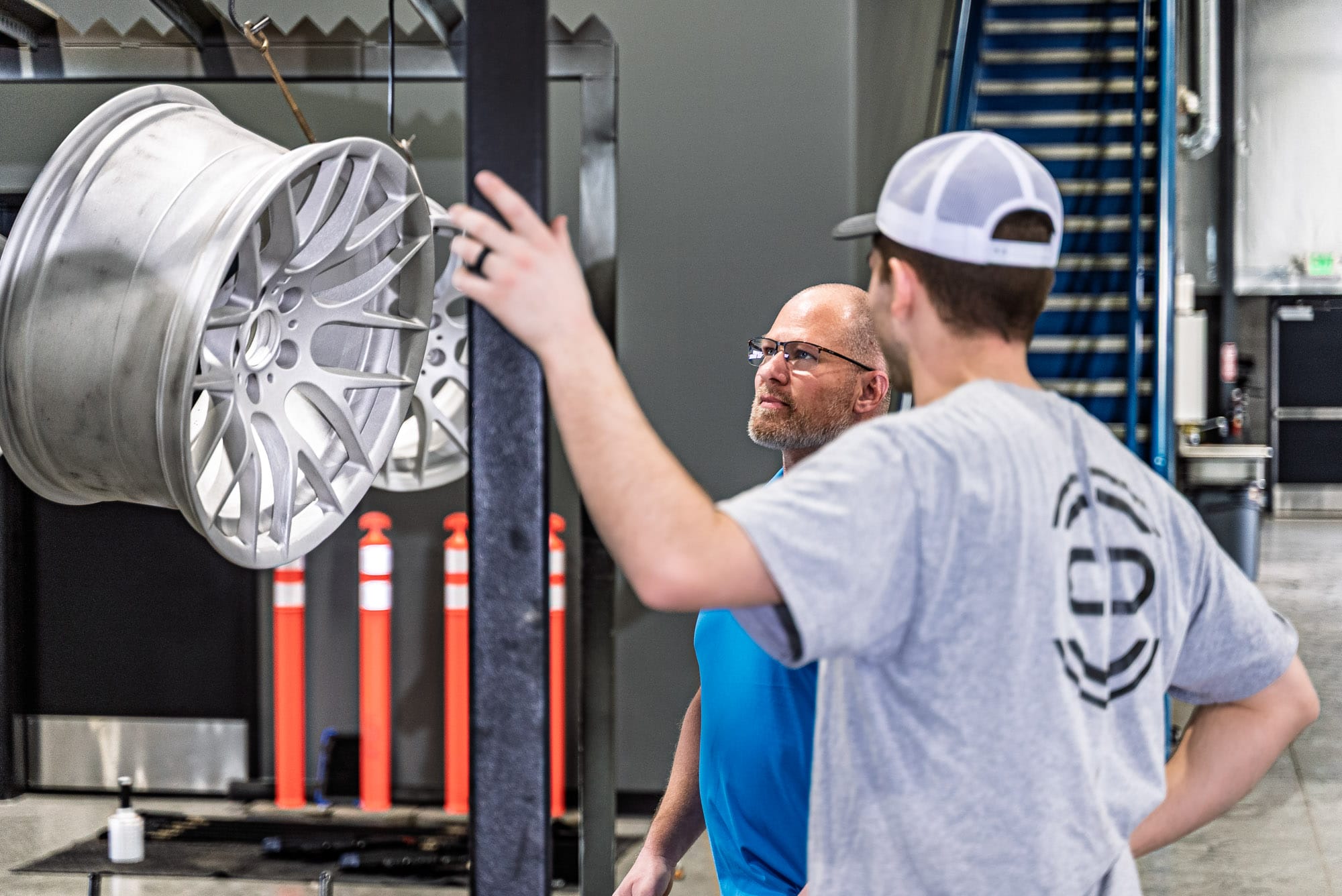Two men inspecting alloy wheel in workshop