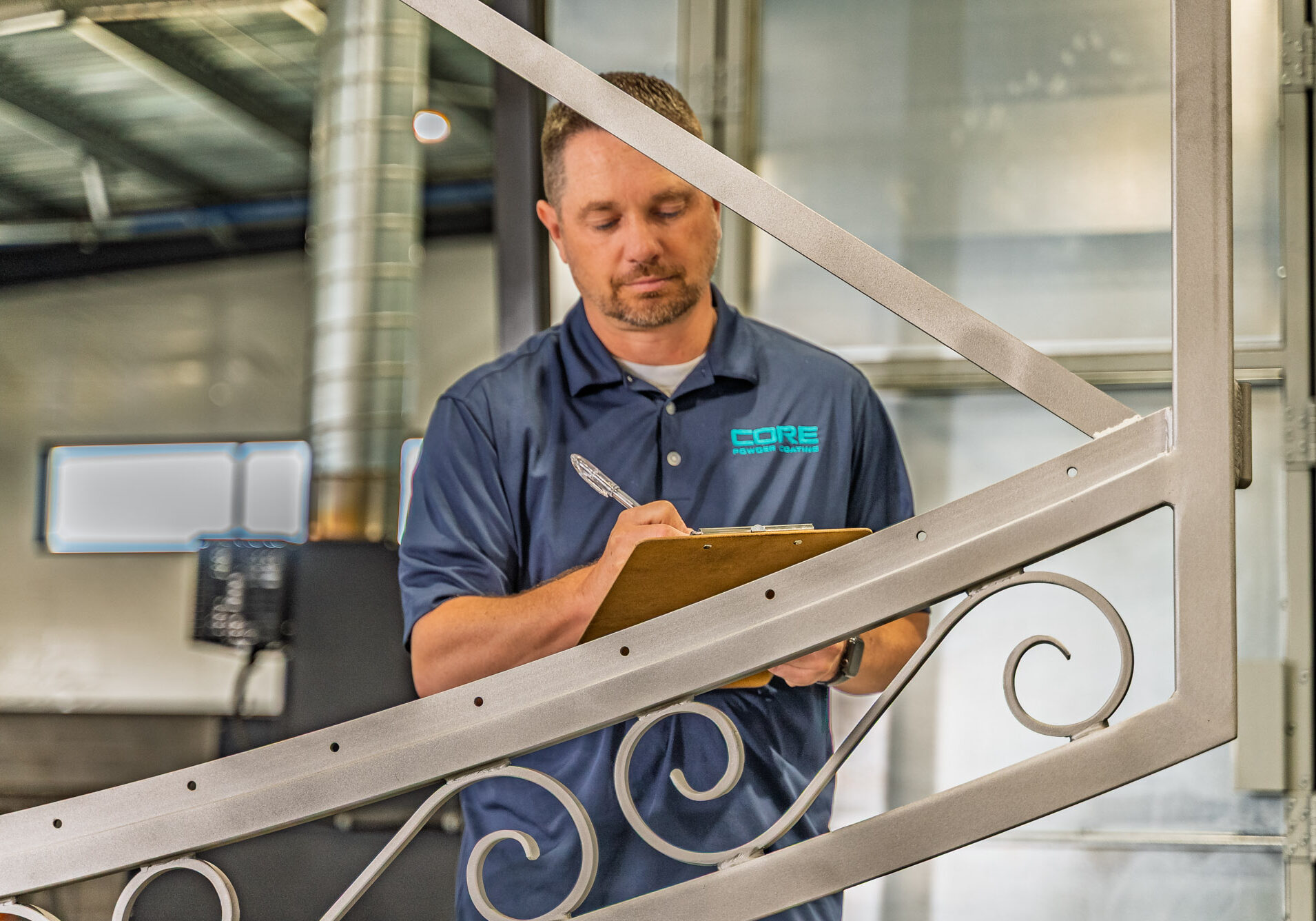 Technician inspecting metal railing with clipboard in workshop